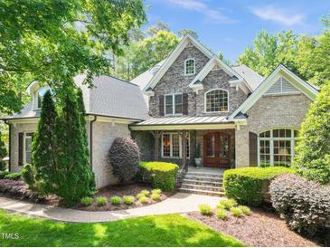 A beautiful brick and stone home with a manicured lawn, lush greenery, and an inviting entryway at 10540 Byrum Woods Dr, Raleigh, NC 27613