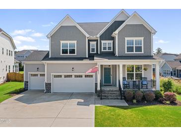 Charming two-story home with a well-maintained lawn, two car garage, and inviting front porch at 109 Obsidian Dr, Holly Springs, NC 27540
