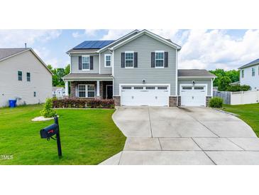 Two-story home with gray siding, black shutters, solar panels, well-manicured lawn, and a two car garage at 1104 Arden Trace Ct, Fuquay Varina, NC 27526