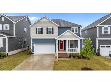 Charming two-story home featuring a red front door, a well-manicured lawn, and an attached garage at 125 Shadowdale Ln, Rolesville, NC 27571