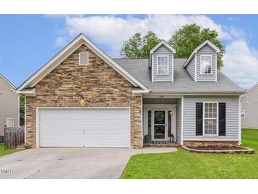 Charming home with stone accents, dormer windows, attached two-car garage, and well-maintained lawn at 149 Hutson Ln, Clayton, NC 27527