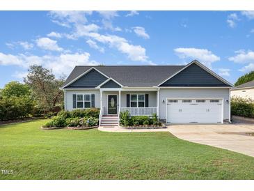 Charming single-story home with a well-manicured lawn, flower beds, and attached two-car garage at 174 Tafton Dr, Wendell, NC 27591