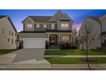 Charming two-story home with a welcoming front porch and well-manicured lawn at twilight at 204 Woodstaff Ave, Wake Forest, NC 27587