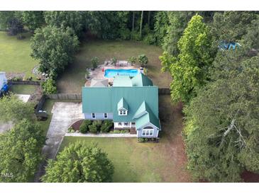 Stunning aerial view of home with beautiful backyard pool, lush landscaping, and a green metal roof at 213 Birch Creek Dr, Fuquay Varina, NC 27526