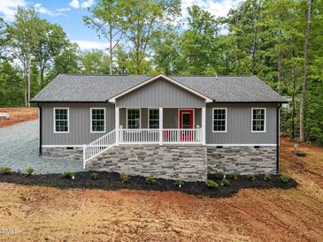 Charming one-story home featuring gray siding, a stone foundation, and a welcoming front porch with a bright red door at 249 Fisherman Point Rd, Roxboro, NC 27574