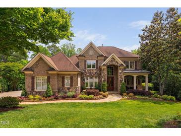 Beautiful brick and stone home with lush landscaping, a charming fountain, and a well-manicured lawn at 3601 Nightfall Ct, Raleigh, NC 27607