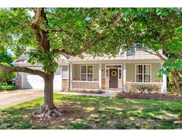 Charming home featuring a welcoming front porch, well-manicured lawn, and mature trees providing ample shade at 5404 Onyx Mill Ct, Raleigh, NC 27616