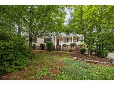 Charming single Gathering home showcasing a covered porch, complemented by lush greenery and a well-manicured lawn at 5804 Heatherbrook Cir, Raleigh, NC 27612
