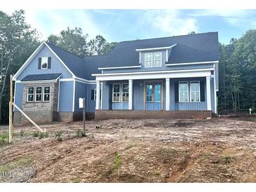 Striking new construction home with blue siding, brick accents, and a covered front porch at 60 Stream View Way, Spring Hope, NC 27882
