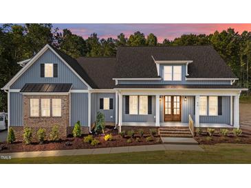 Charming exterior of a blue home with brick accents, landscaped yard, and inviting front porch at 60 Stream View Way, Spring Hope, NC 27882