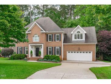 Charming two-story brick home featuring black shutters, a manicured lawn, and an attached two-car garage at 7929 Pine Timber Dr, Raleigh, NC 27613