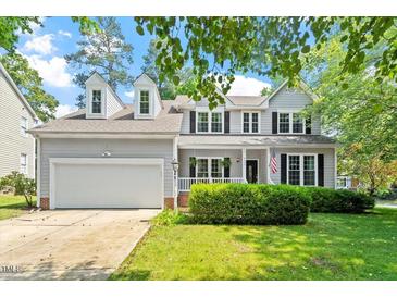 Charming two-story home featuring a manicured lawn, inviting front porch, and a classic American flag display at 9400 Leslieshire Dr, Raleigh, NC 27615