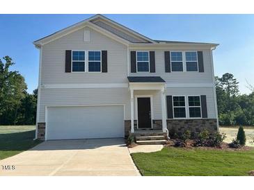 Charming two-story home with a two-car garage, lush lawn, and stone veneer accents at 95 Cordoba Dr, Franklinton, NC 27525