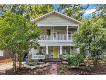 Charming two-story home with a vibrant yellow front door and welcoming double-decker front porches at 1011 Burch Ave, Durham, NC 27701