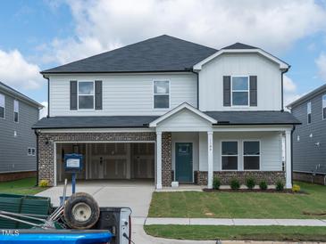 Two-story home showcasing modern design, attached two car garage, and an inviting covered front porch at 1104 Landen Creek Ln, Zebulon, NC 27597