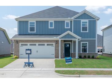 Charming two-story home featuring blue siding, brick accents, a two-car garage, and a well-maintained front lawn at 1108 Landen Creek Ln, Zebulon, NC 27597