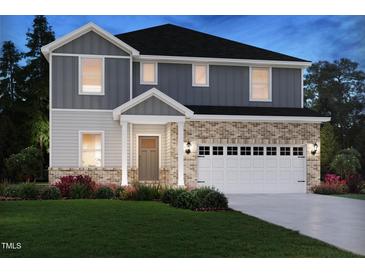 Two-story home showcasing a brick and gray facade, a two-car garage, and a well-manicured lawn at dusk at 1108 Landen Creek Ln, Zebulon, NC 27597