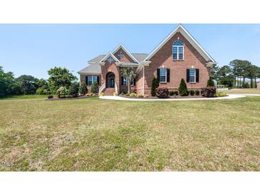 Brick home featuring manicured lawn, mature trees, and beautiful architectural details at 120 Gentle Rain Dr, Garner, NC 27529