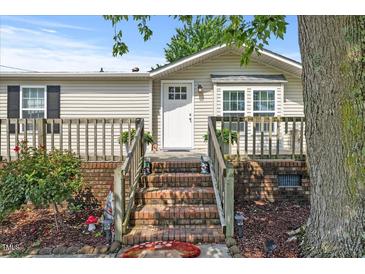 Charming single-story home with brick stairs and a cozy front porch, complemented by lush landscaping and a welcoming front door at 12294 Nc Hwy 96 S, Dunn, NC 28334