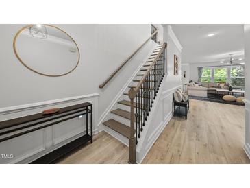 Bright entryway features stylish staircase, hardwood floors, and a decorative round mirror for a welcoming ambiance at 2634 Turner Pines Dr, New Hill, NC 27562