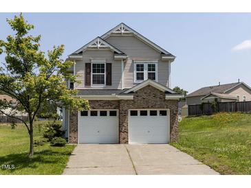Two-story home with vinyl siding, brick base, and two-car garage beneath a blue sky on a sunny day at 3507 Portico Ln, Durham, NC 27703