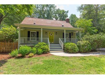 Charming front exterior view of a quaint home, featuring a well-manicured lawn and covered front porch with yellow door at 520 Brittany Bay W, Raleigh, NC 27614