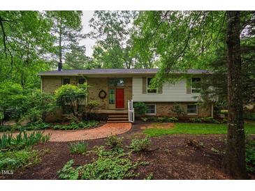 Charming brick home with a well-manicured lawn, mature trees, and a welcoming red front door at 803 Churchill Dr, Chapel Hill, NC 27517