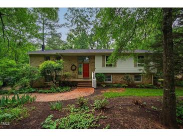 Charming two-story home with brick accents, complemented by a red front door and lush landscaping at 803 Churchill Dr, Chapel Hill, NC 27517