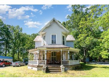 Charming two-story home featuring a classic front porch and mature trees on a sunny day at 110 E Church St, Creedmoor, NC 27522