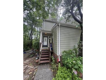 View of the home's front door with wooden steps and an inviting, landscaped entrance surrounded by lush greenery at 130 Beechwood Dr, Carrboro, NC 27510
