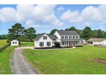Beautiful two-story white farmhouse with black shutters, a charming front porch, and a lush green lawn at 4600 Smithfield Rd, Wendell, NC 27591
