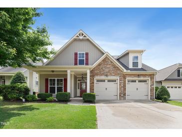 Charming home showcasing manicured lawn, stone accents, a two-car garage, and red shutter details against a blue sky at 13 Nettletree Creek Ct, Youngsville, NC 27596