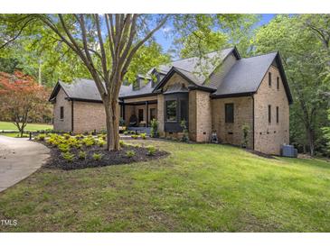 Charming brick home with a well-manicured lawn and mature trees, offering a serene and inviting curb appeal at 13121 Melvin Arnold Rd, Raleigh, NC 27613