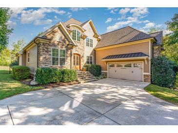 Stunning stone and tan home featuring a two-car garage, manicured lawn, and steps leading to the front door at 268 The Preserve Trl, Chapel Hill, NC 27517