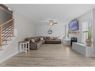 Bright living room features wood-look flooring, large sectional sofa, shiplap accent wall, and a cozy fireplace at 55 Prospectus Ln, Franklinton, NC 27525