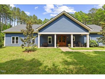 Charming blue home featuring a well-manicured lawn and a welcoming front porch with a striking wood front door at 741 Sinai Cir, Hillsborough, NC 27278
