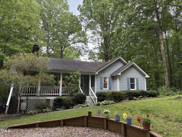 Charming home with landscaped front yard, covered porch, and light blue siding surrounded by lush trees at 8812 Valley Hill Ct, Apex, NC 27539