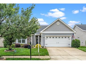 Charming home featuring a two-car garage, stone accents, manicured lawn, and mature landscaping, offering great curb appeal at 2033 Buck Corner Ln, Fuquay Varina, NC 27526