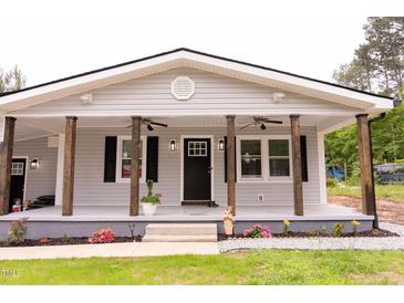 Charming home with a covered front porch featuring wooden pillars, ceiling fans, and freshly planted flowers at 3030 Forrester St, Durham, NC 27704