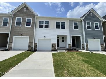 Three townhouses featuring diverse siding, attached garages and freshly cut green lawns on a bright day at 377 Thompson Overlook Way, Smithfield, NC 27577