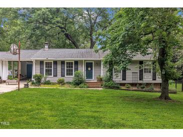 Charming single-story home with lush front lawn, mature trees, and traditional architectural details at 5002 Kendridge Dr, Durham, NC 27712