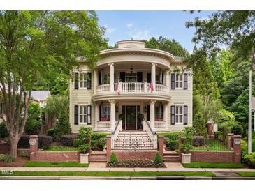 Stately two-story home featuring a double veranda, brick fence, beautiful landscaping, and black shutters at 8308 Society Pl, Raleigh, NC 27615