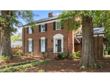 Charming brick home with manicured lawn, trimmed shrubs, and tree-lined front yard, with a black front door at 925 S Chestnut St, Henderson, NC 27536