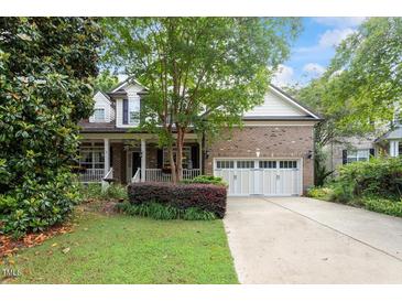 Charming brick home with a manicured lawn, inviting front porch and a two-car garage at 12212 Ashton Woods Ln, Raleigh, NC 27614