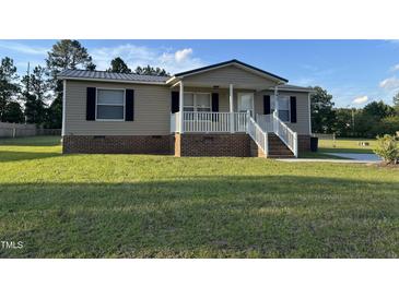 Charming single-story home featuring a cozy front porch and well-maintained lawn on a sunny day at 195 Washington Ln, Cameron, NC 28326
