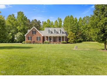 Charming brick home featuring a welcoming front porch and lush, green lawn at 200 Daniel Ridge Ln, Roxboro, NC 27574