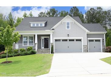 Charming home featuring a two-car garage, stone accents, a cozy porch, and manicured landscaping at 309 Hines Point Dr, Rolesville, NC 27571