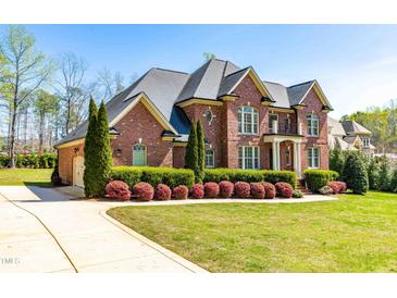 Beautiful two-story brick home featuring manicured landscaping and an attached three-car garage at 3908 Chaumont Dr, Apex, NC 27539