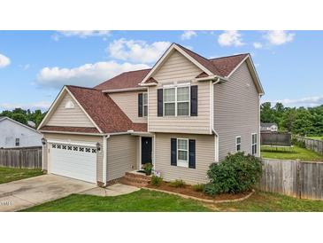 Charming two-story home featuring tan siding, brown roof, attached two car garage, and manicured landscaping at 5321 Longspur Dr, Snow Camp, NC 27349
