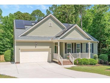 Charming home featuring a 2-car garage, solar panels and a welcoming front porch surrounded by a lush, landscaped lawn at 6512 Blalock Forest Dr, Willow Springs, NC 27592